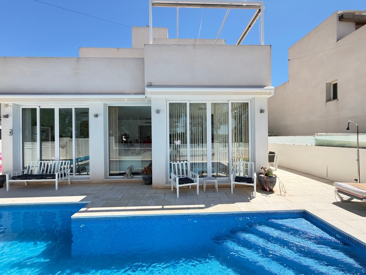 Modern villa with a swimming pool and a sun-drenched terrace, featuring large windows and outdoor seating.
