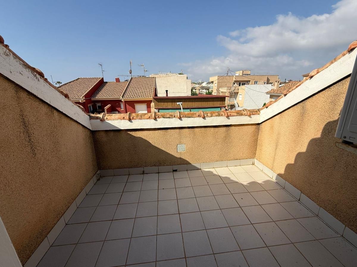 Tiled terrace with a view of residential buildings under a blue sky with clouds.