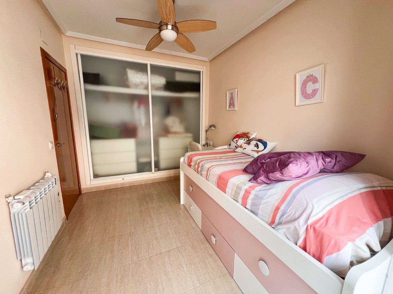 Gezellige kinderkamer met bed, kast en plafondventilator