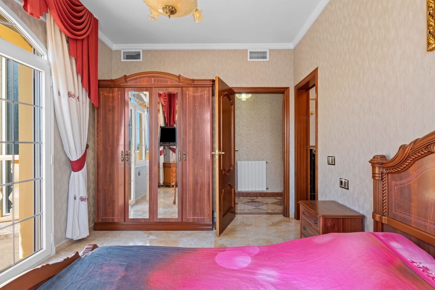 Slaapkamer met sierlijke kledingkast, balkon en klassiek interieur.