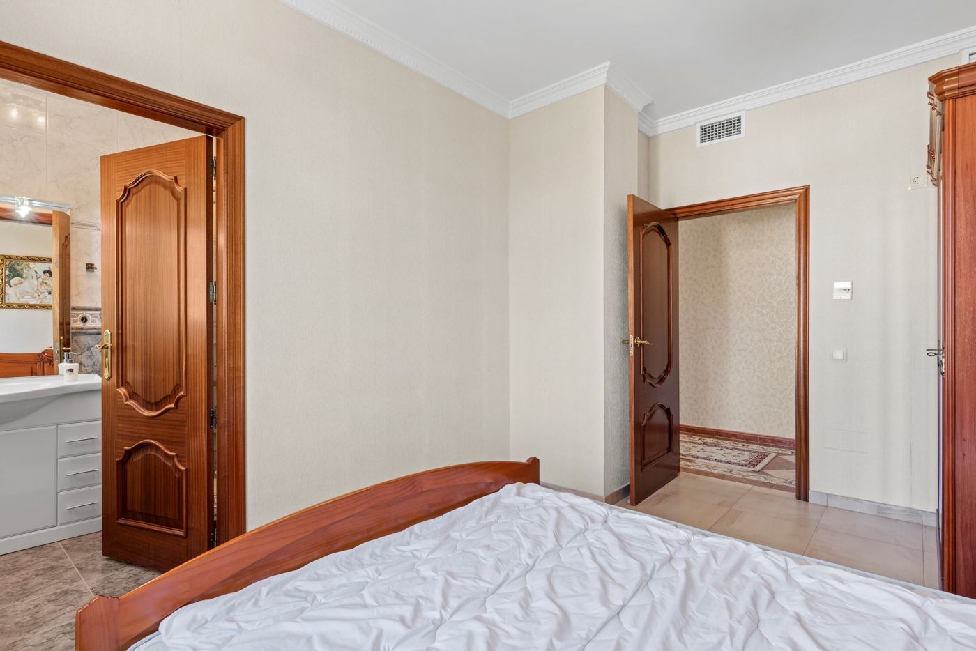 Slaapkamer interieur met houten bed en open badkamerdeur.