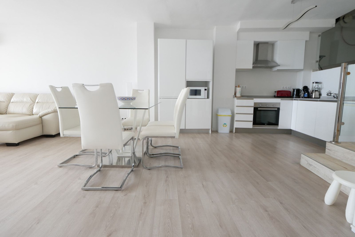 Modern appartement interieur met witte meubels en een glazen tafel.