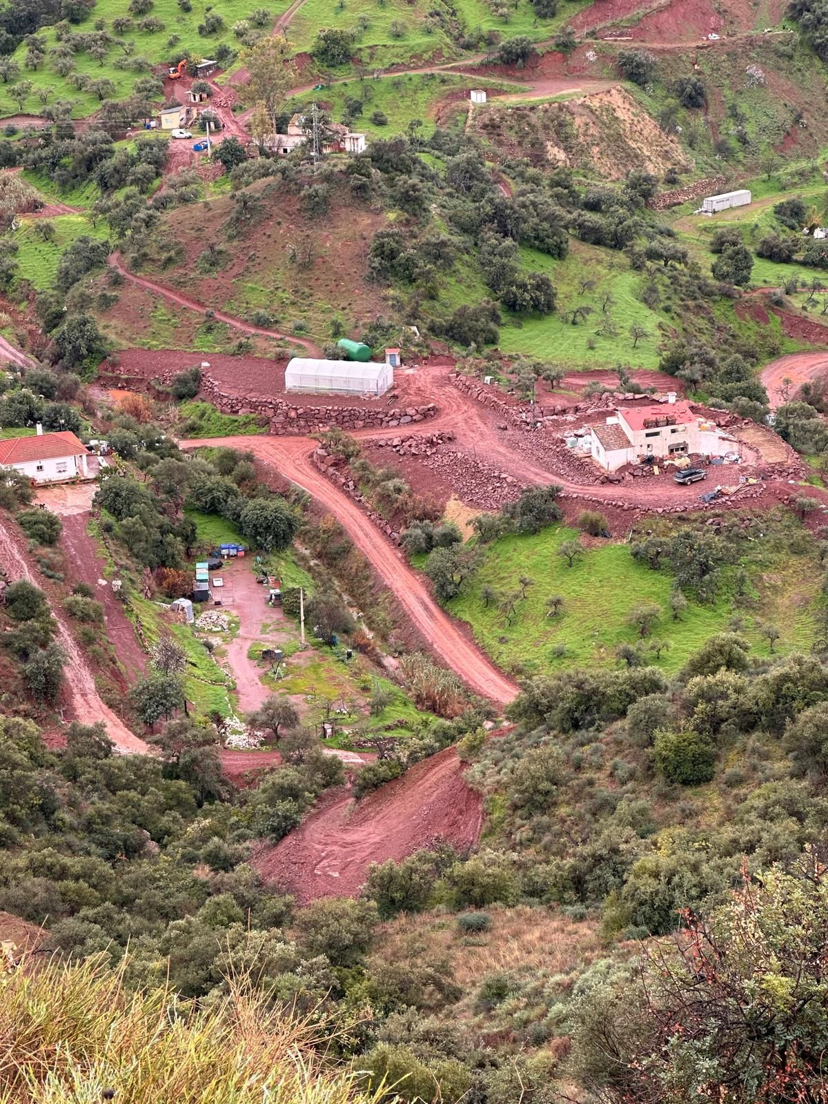 Luchtfoto van landelijk gelegen woning met omliggend groen en zanderige paden.