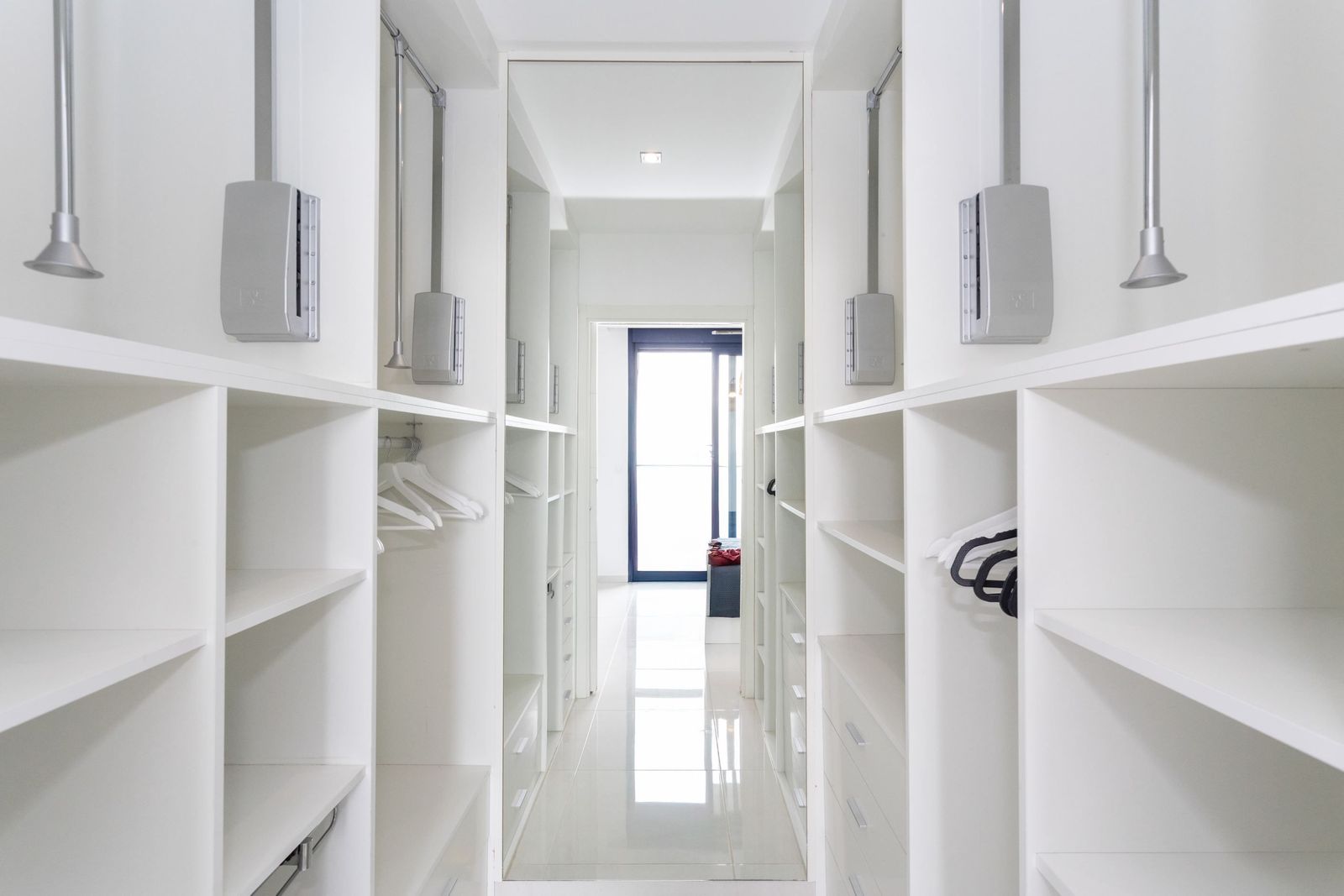 Moderne witte inloopkast met planken en hangruimte.