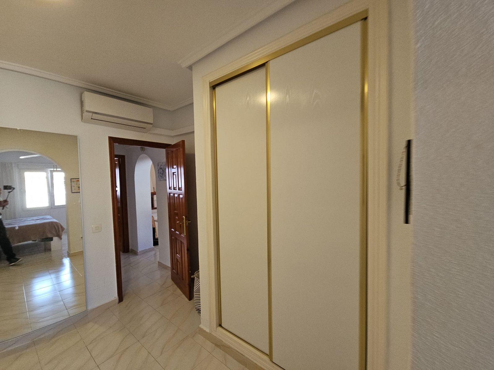 Interieur van een gang met kast en doorkijk naar een slaapkamer.