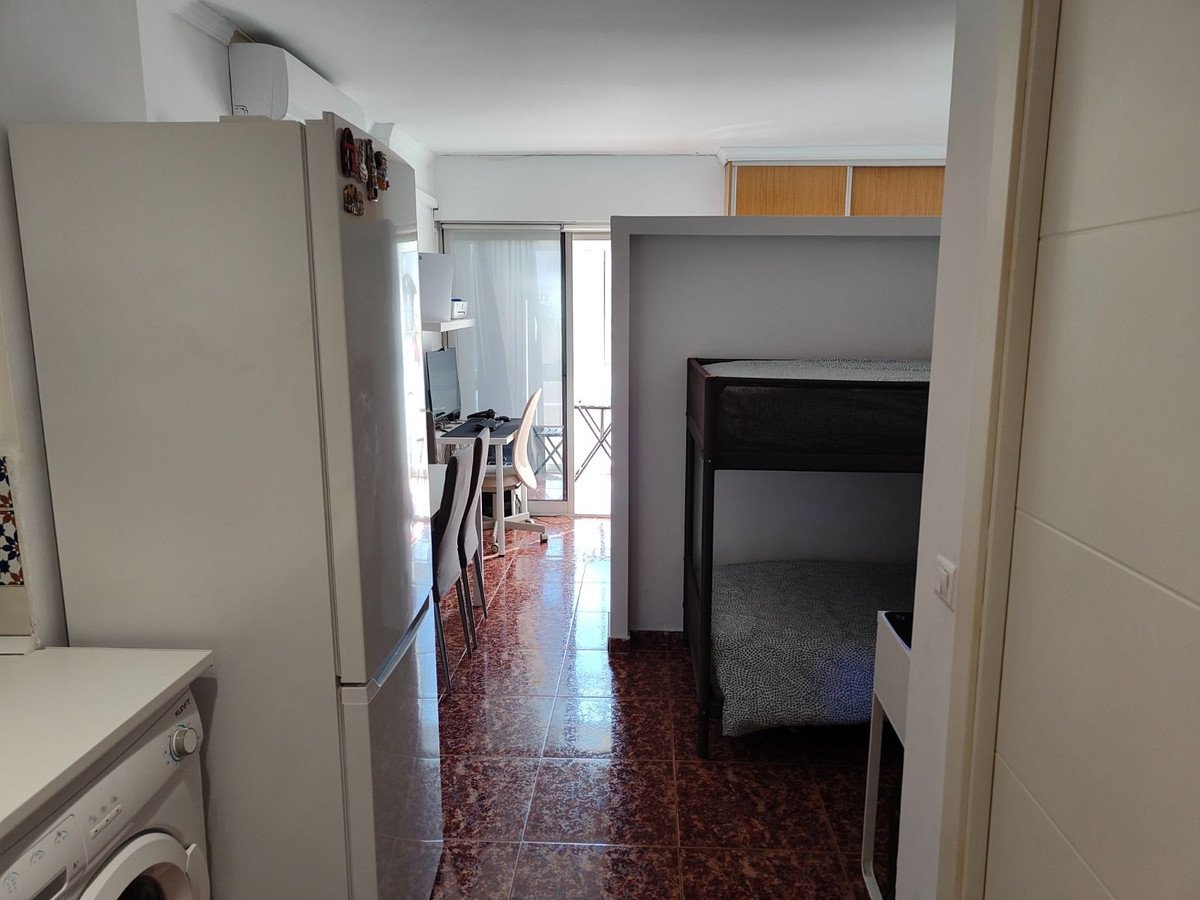 Bunk beds, kitchenette, and a desk with a balcony visible in the background.