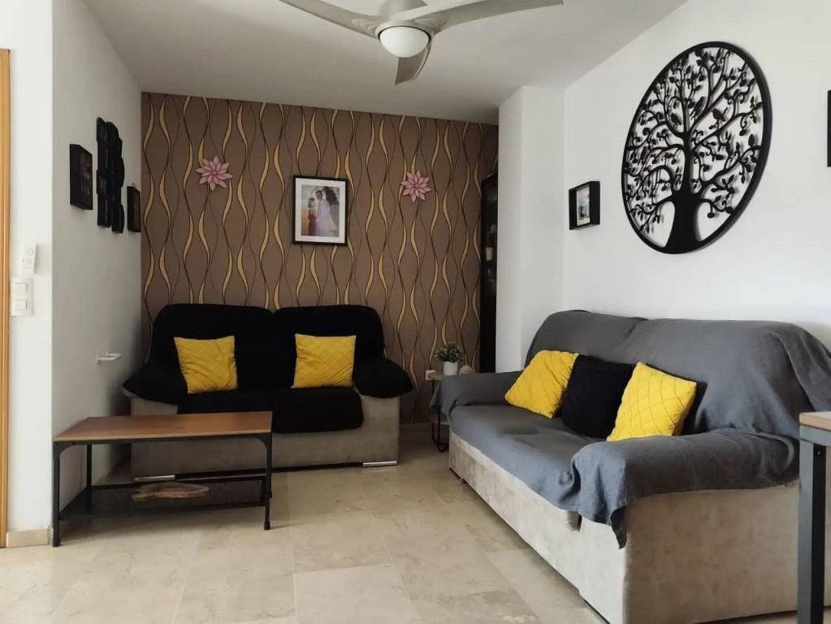 Modern living room with patterned wallpaper, two sofas, decorative tree wall art, and yellow accent pillows.
