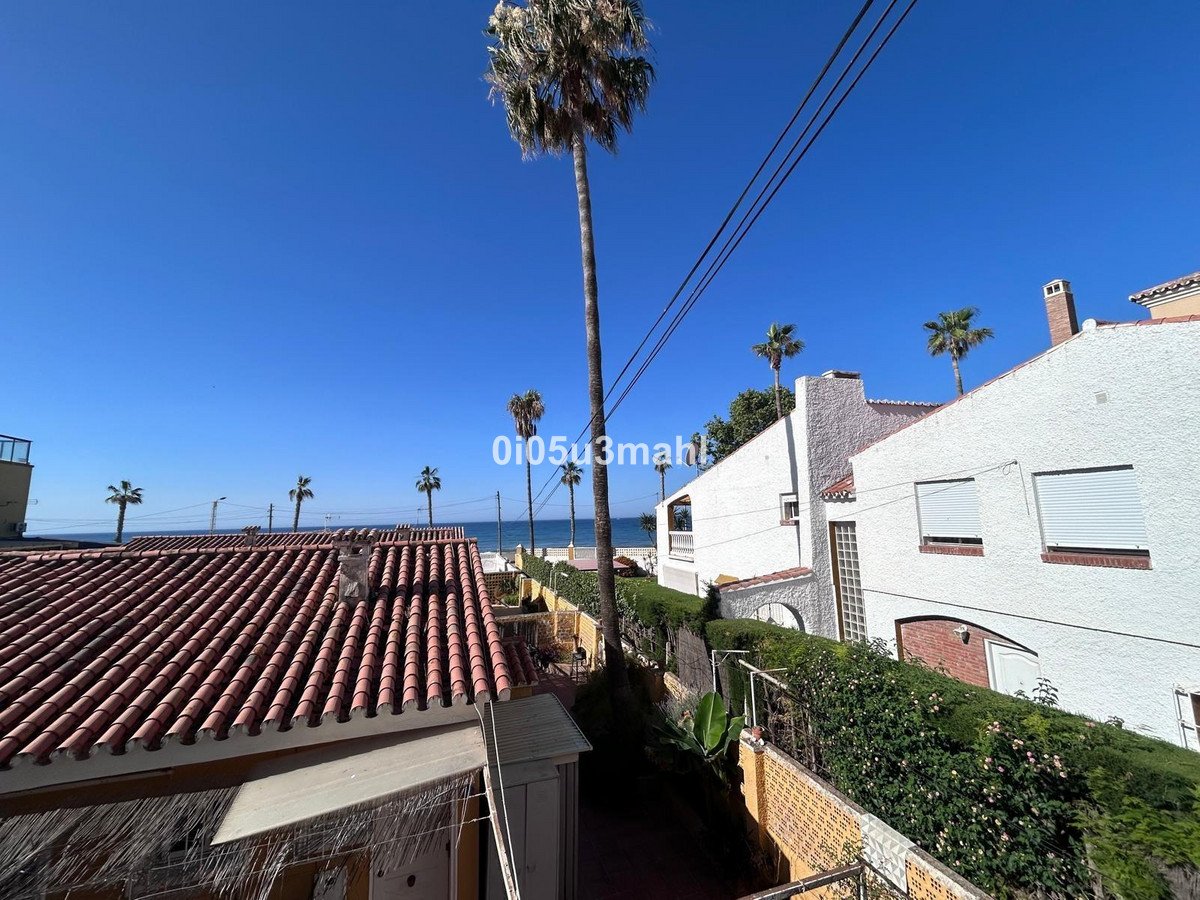 View from a terrace with palm trees and the sea in the background. Clear blue sky.