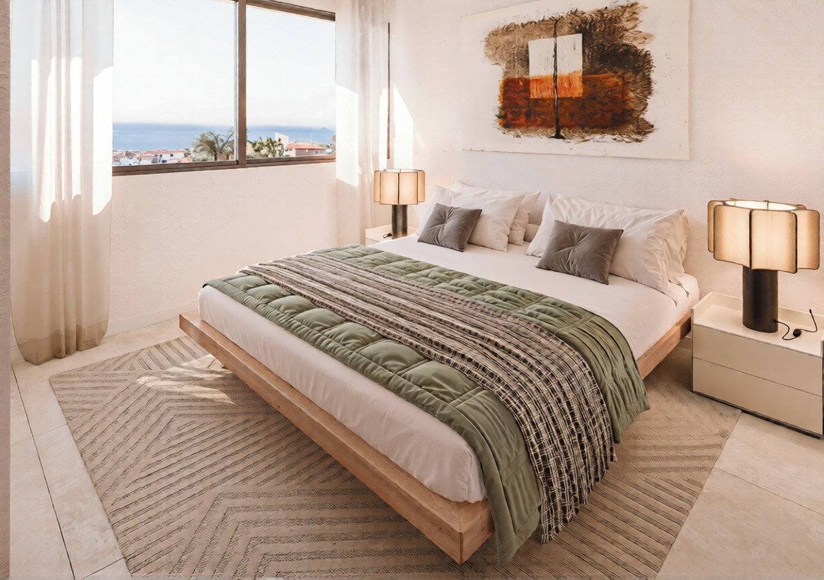 Modern bedroom with a large bed, ocean view from the window, and contemporary art on the wall.