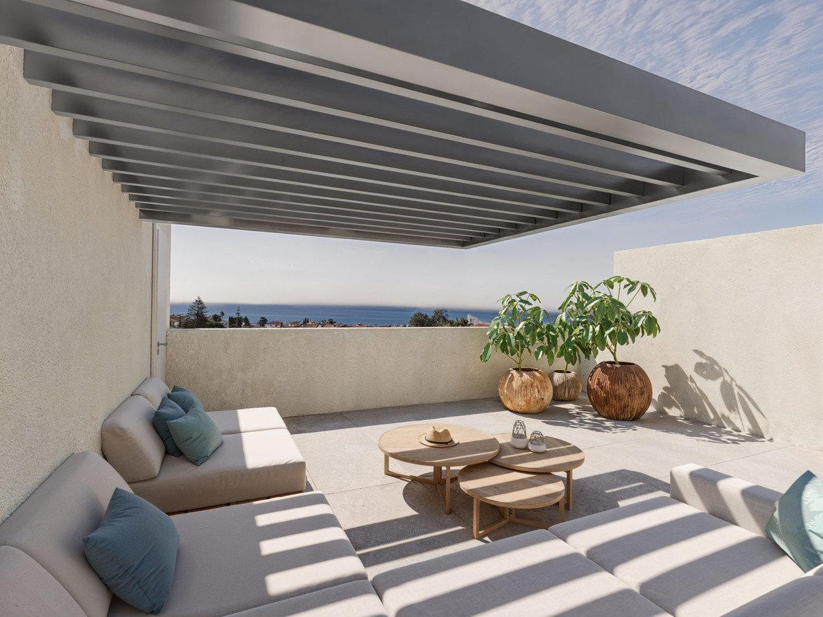 Modern terrace with a pergola, comfortable lounge seating, coffee tables, potted plants, and a beautiful sea view.