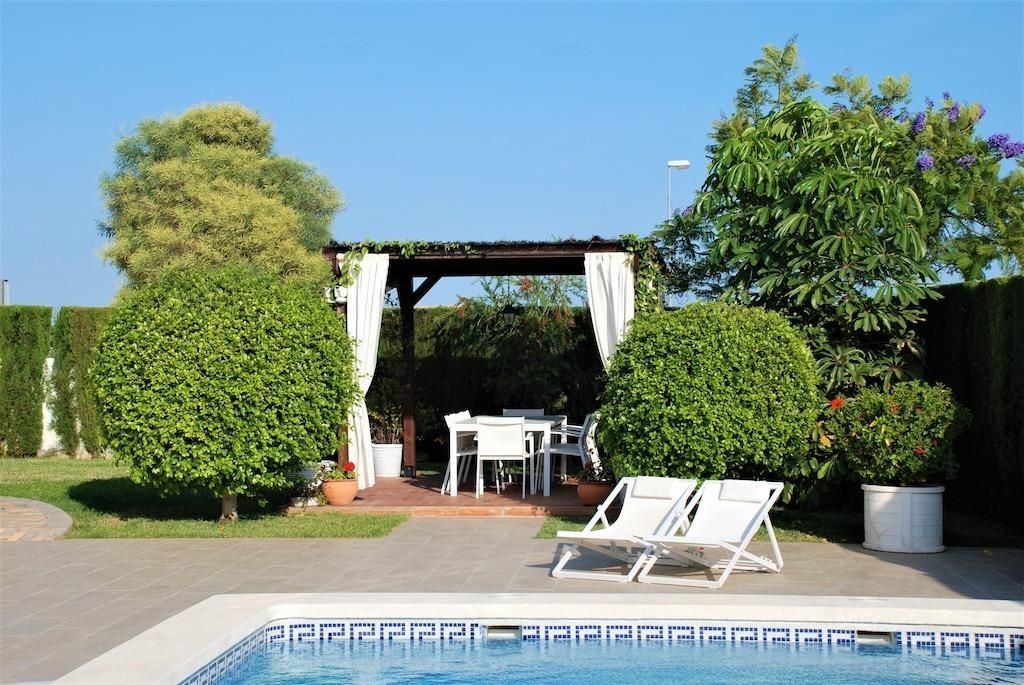Terras bij het zwembad met pergola en tuinstoelen.