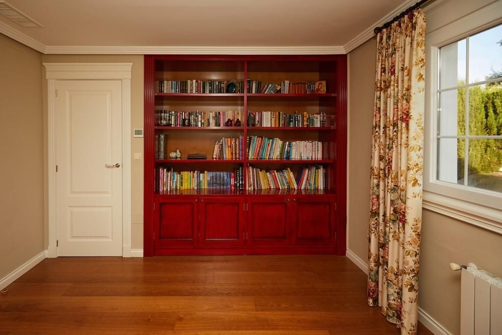 Rode boekenkast met houten vloer in een kamer met een raam.