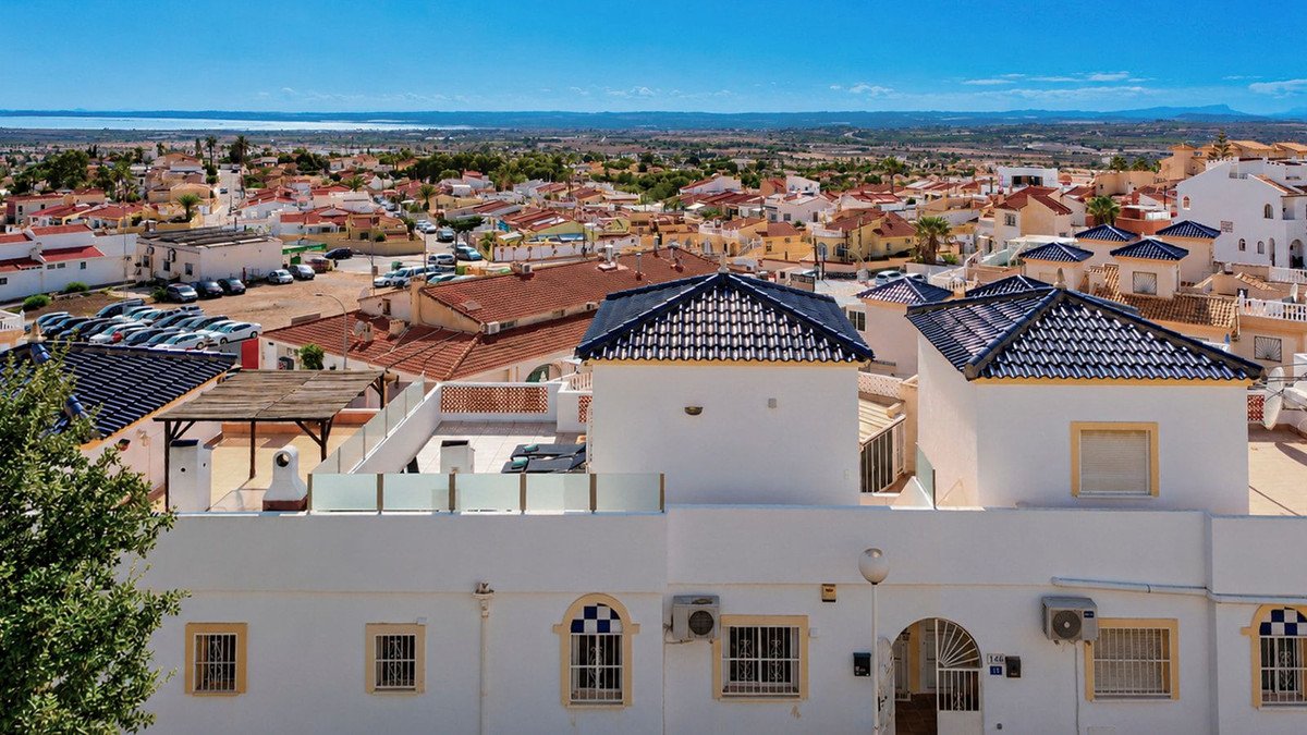 Rooftop terrace with lounge chairs and sea views overlooking a town on a clear day.