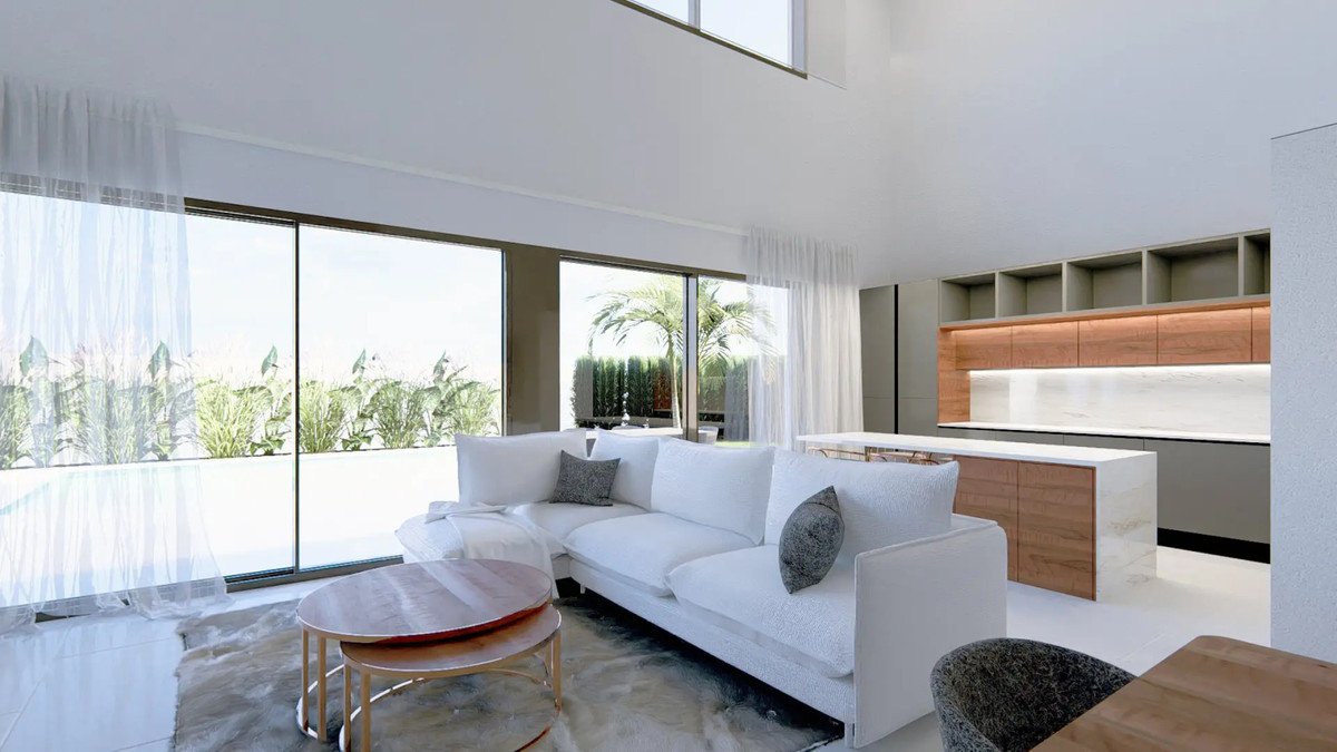 Modern living room with white sofa, wooden tables, and large windows overlooking a garden.