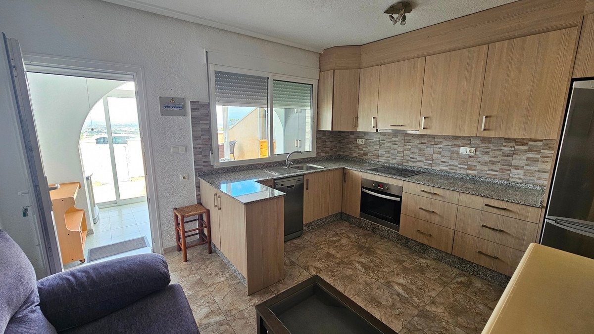 A modern kitchen featuring light wood cabinets, granite countertops, a dishwasher, oven, and a balcony door with an outdoor view.