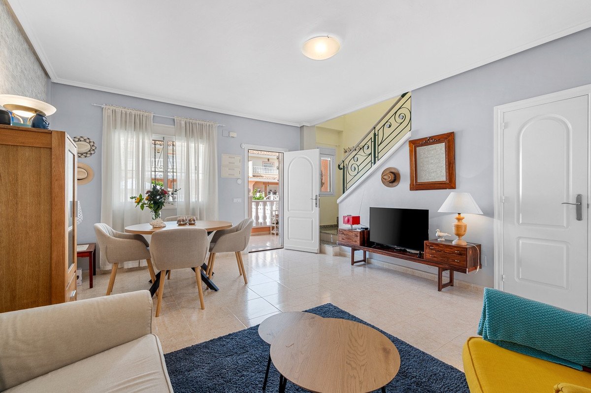 Living and dining area with modern furniture, a staircase, and open doors leading to an outdoor space.
