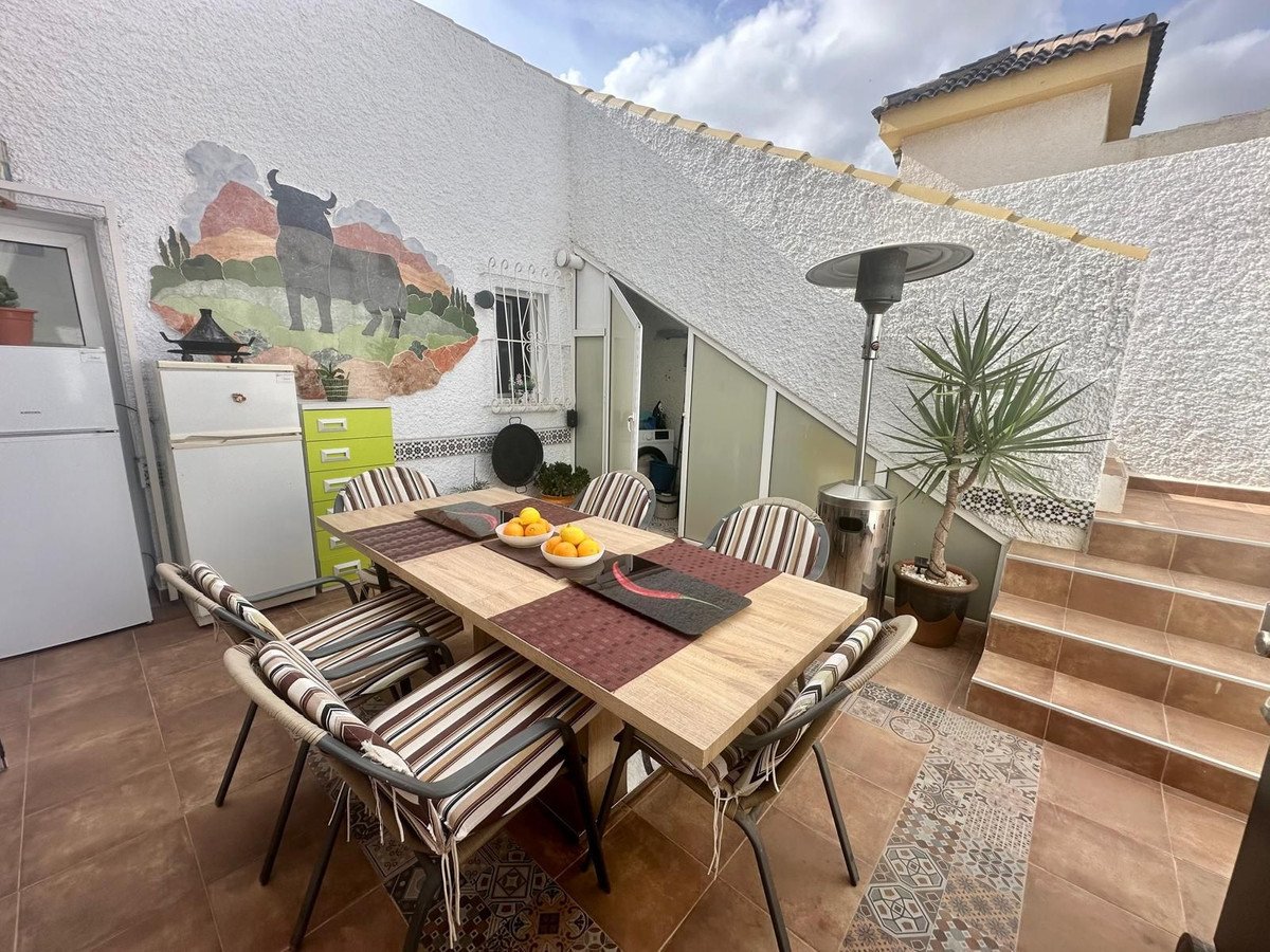 Outdoor dining area on a terrace with a bull mural, table, chairs, and stairs leading to a higher level.