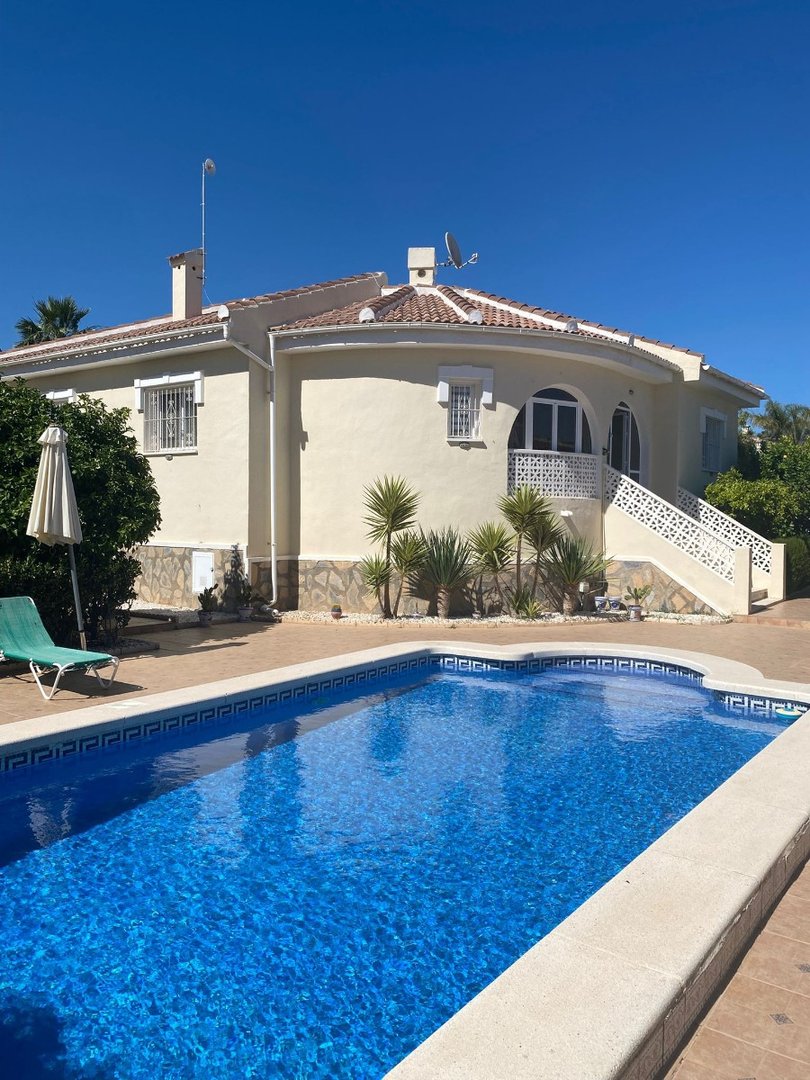 A bright sunny day shows a villa with a private swimming pool and outdoor seating area.