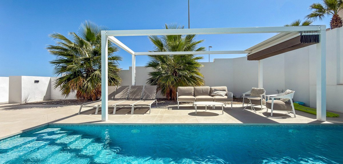 Outdoor patio with pool, lounge chairs, sofa, and palm trees under pergola