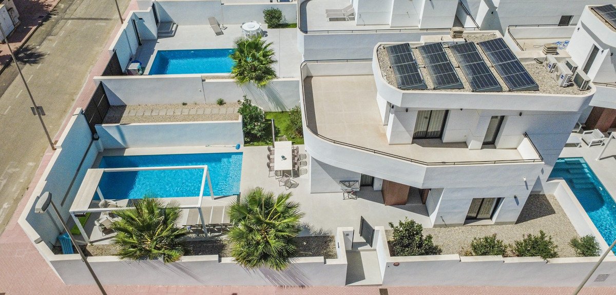 Aerial view of a modern villa with swimming pools and solar panels on the roof