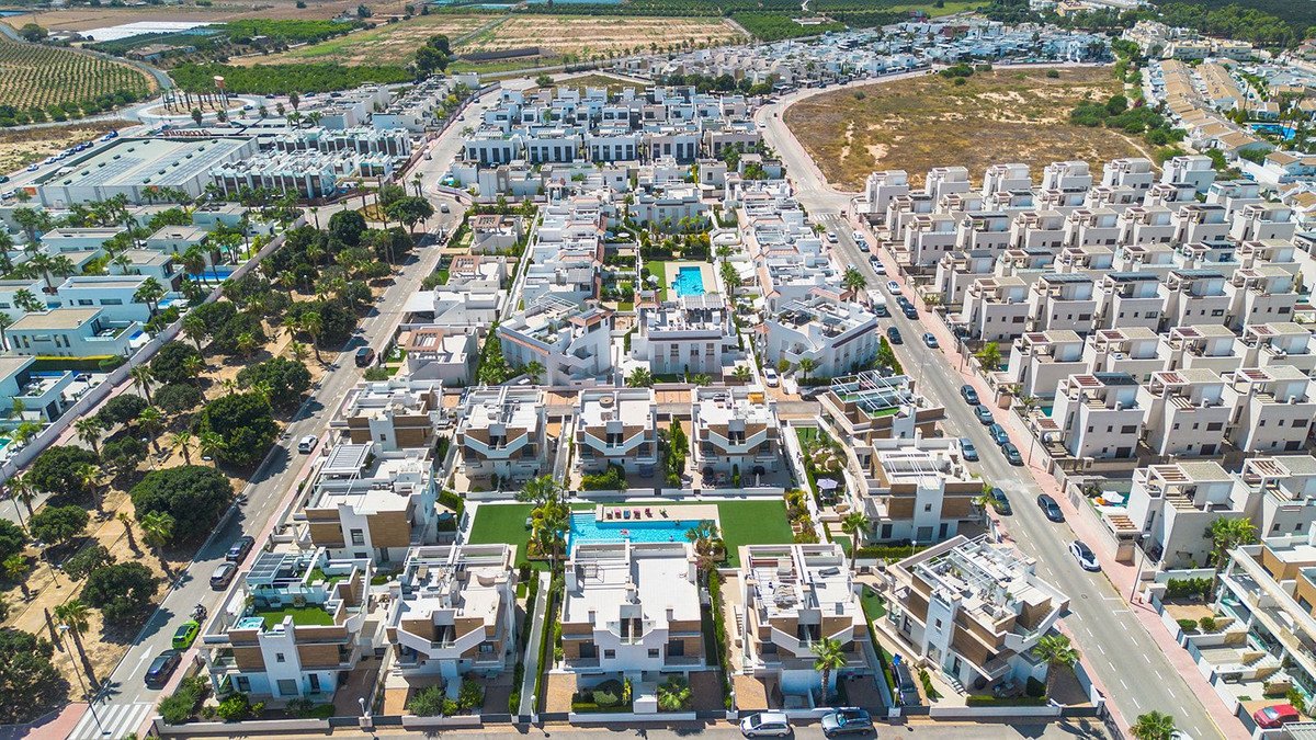 Aerial view of a modern residential complex with townhouses, swimming pools, and manicured lawns.
