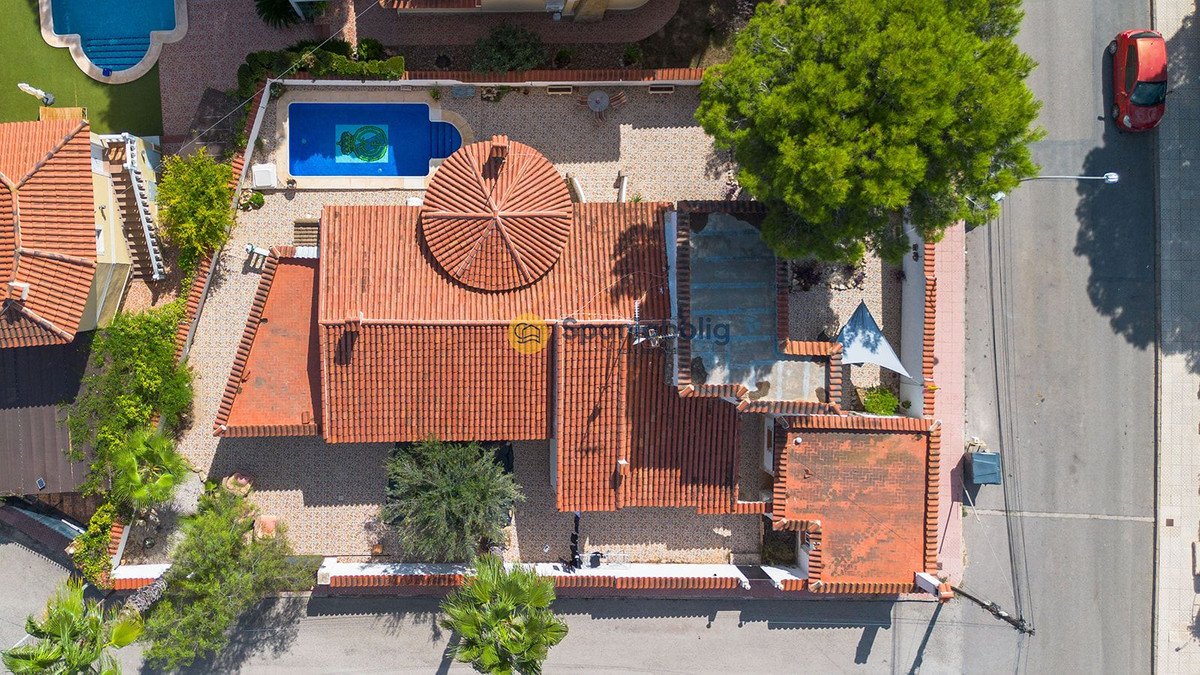 Aerial view of a villa with a swimming pool, courtyard, and red tiled roofs.