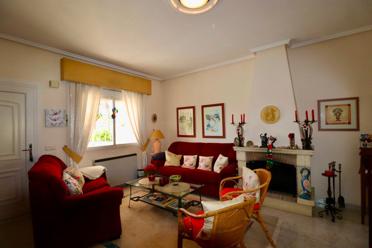 Red sofa and armchair in living room with fireplace, artwork, and window view.