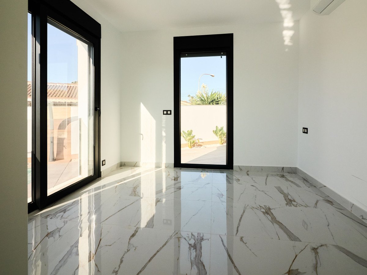 Empty modern room with large windows showing a pool area and an outdoor garden. Marble floors reflect sunlight.