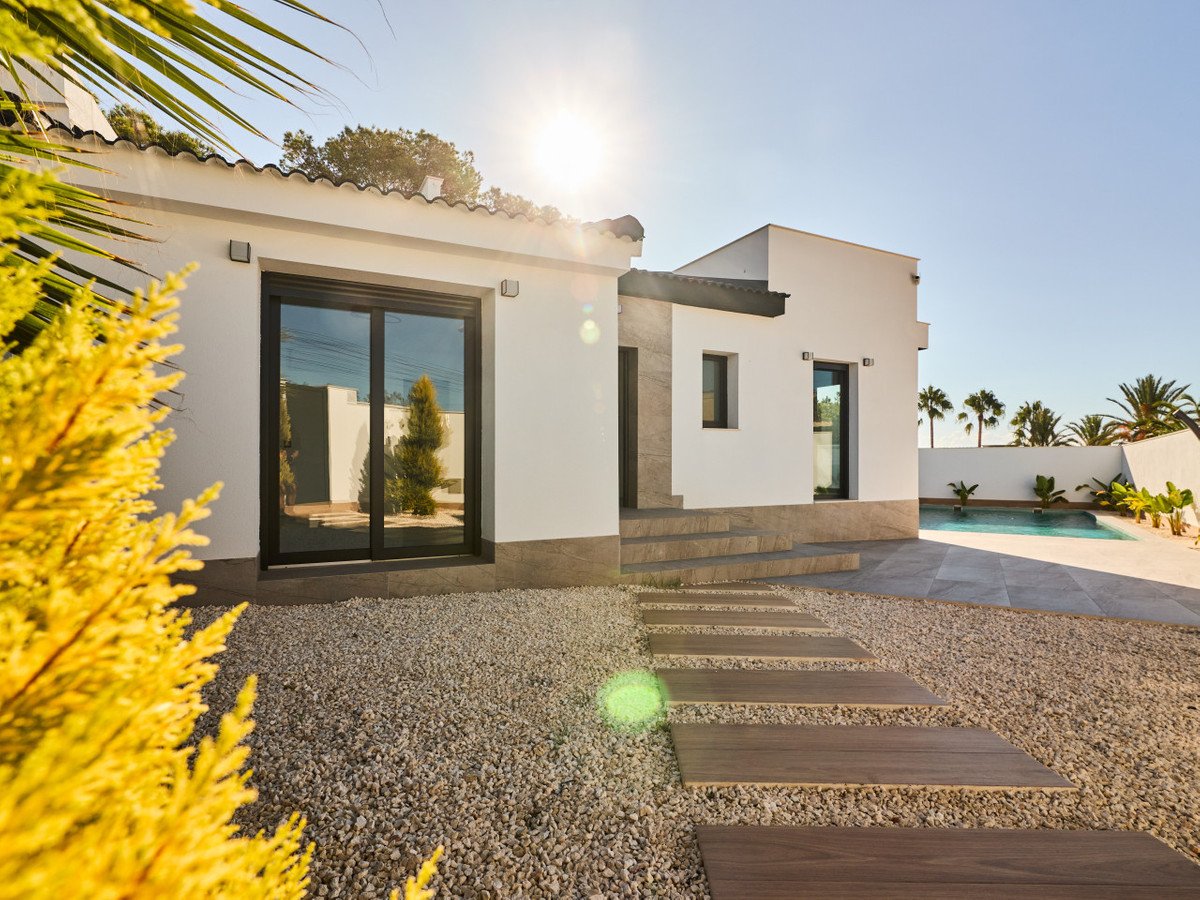Modern white house exterior with a swimming pool, palm trees, and a sunny sky.