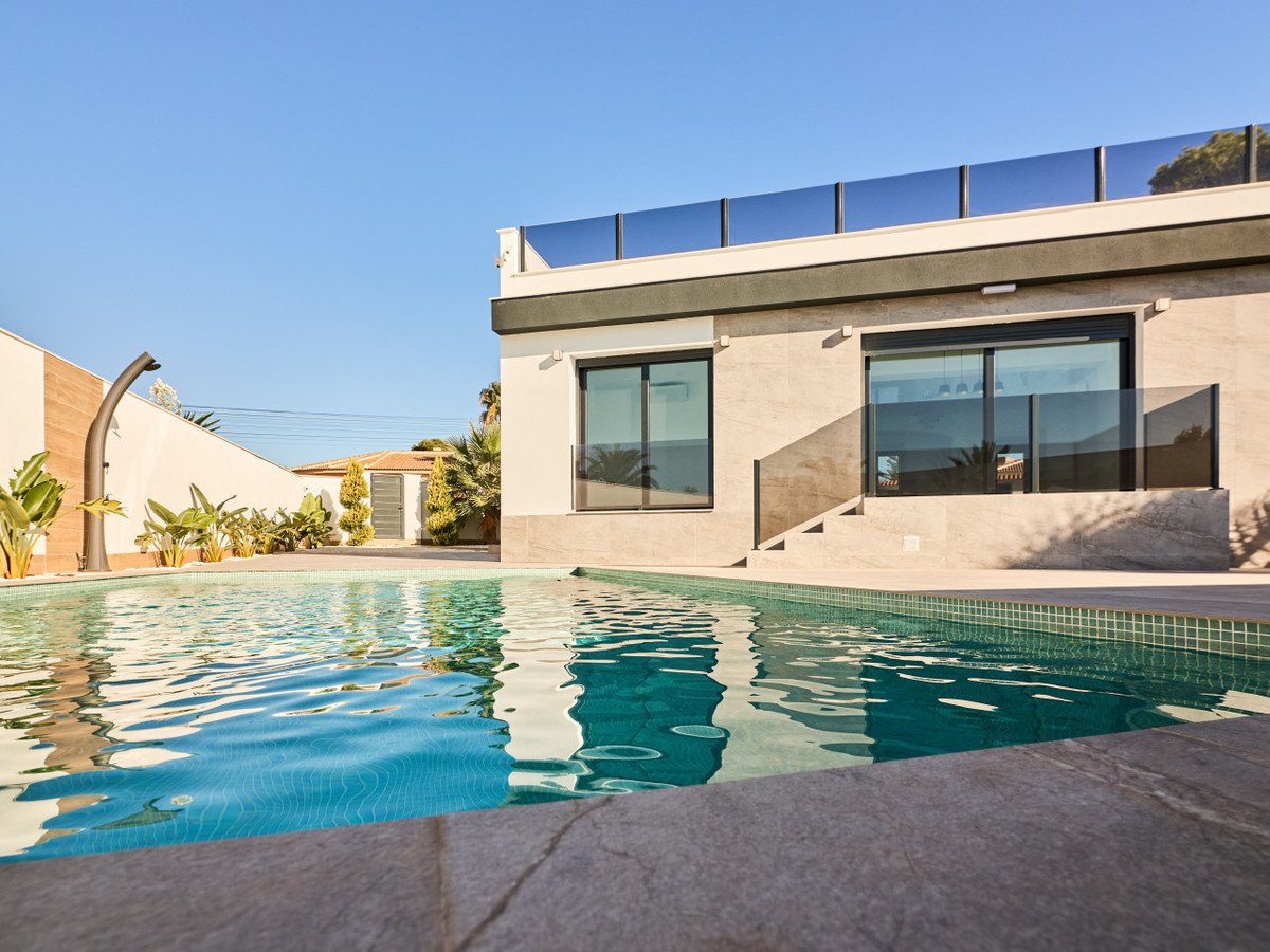 Modern villa with a refreshing swimming pool, surrounded by lush greenery and a clear blue sky.