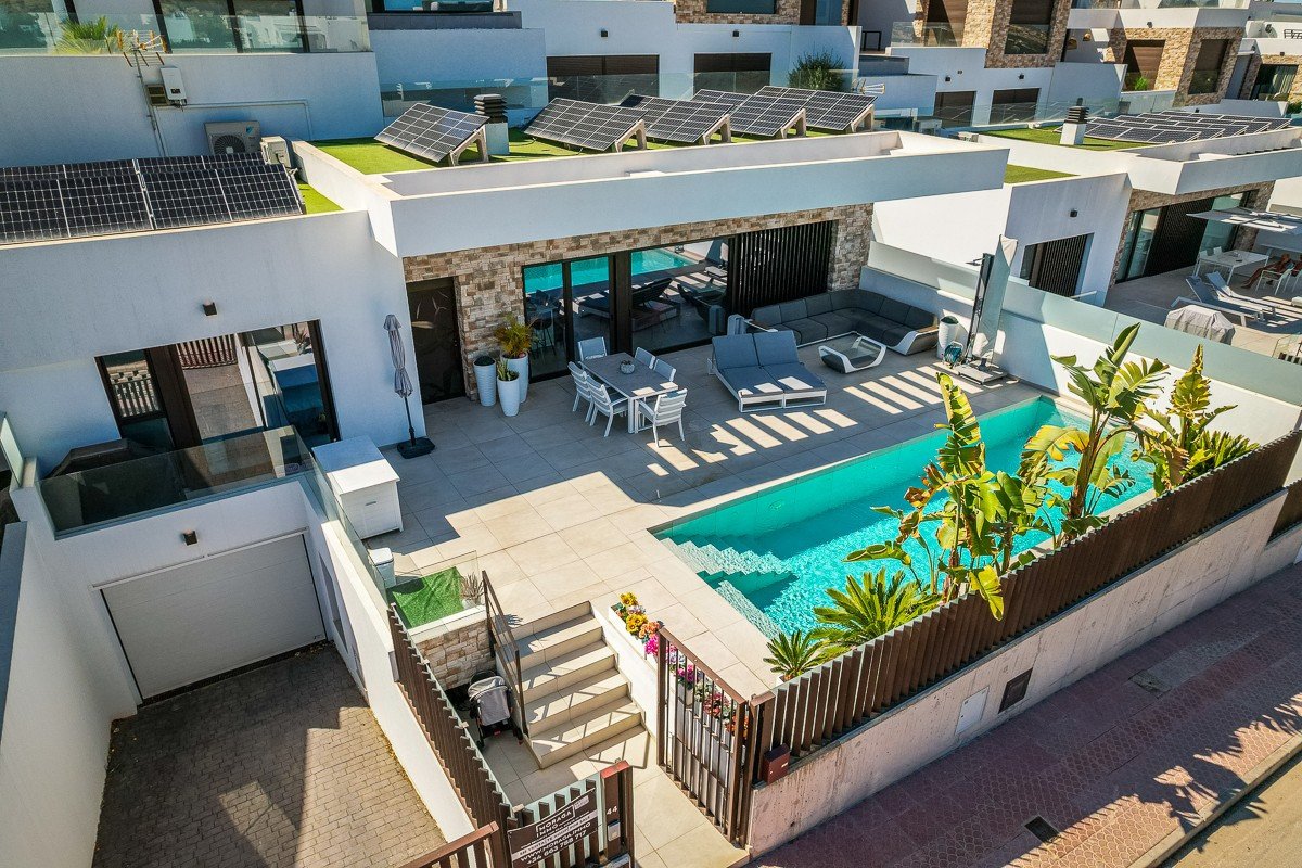 Modern villa with swimming pool, outdoor lounge area, dining table, and solar panels on the roof.