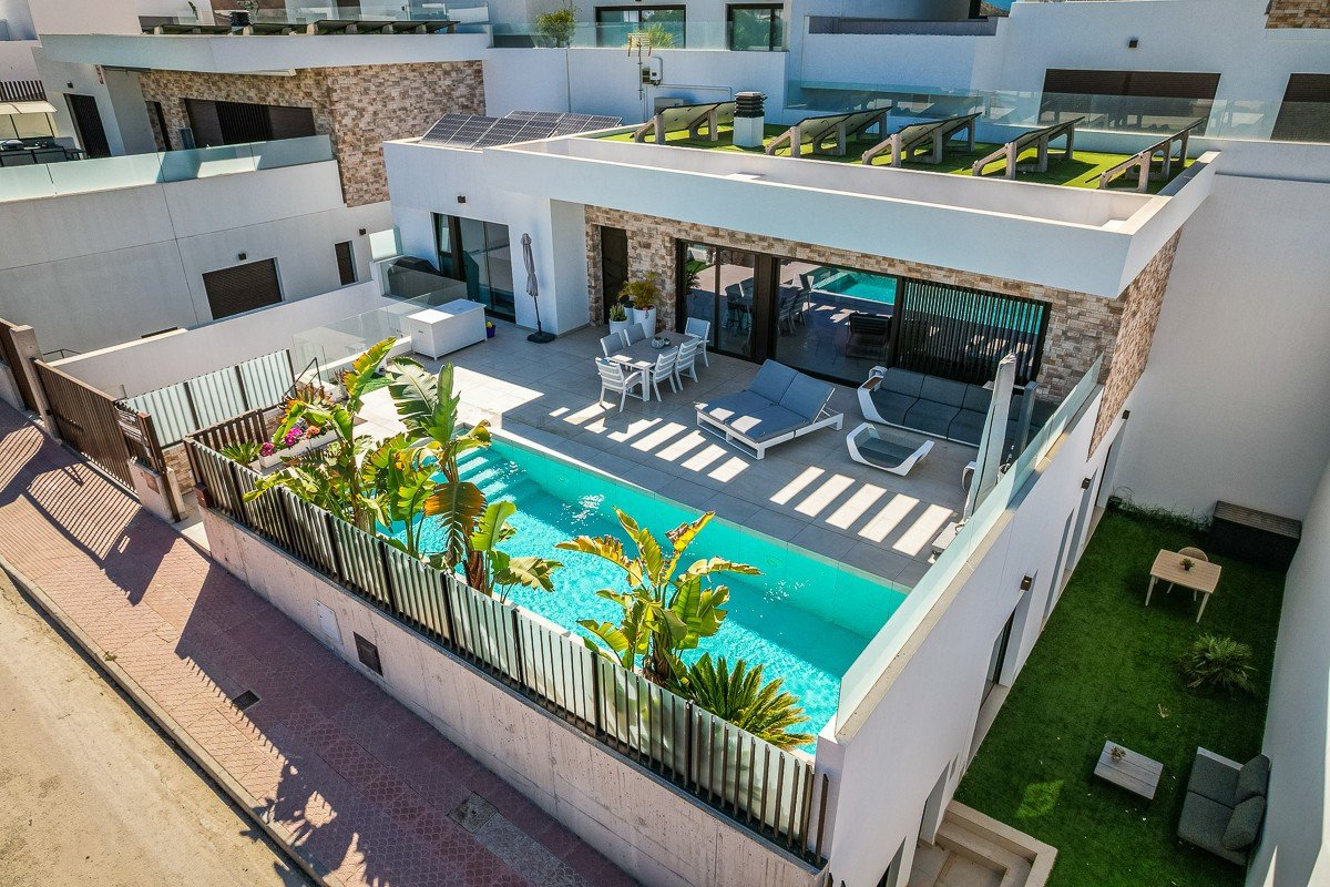 Modern villa with private swimming pool, sun loungers, outdoor dining area, and rooftop solar panels.