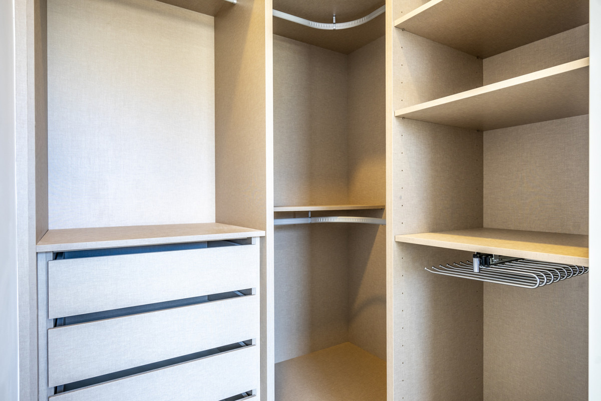 Beige inloopkast ontwerp met laden en planken.