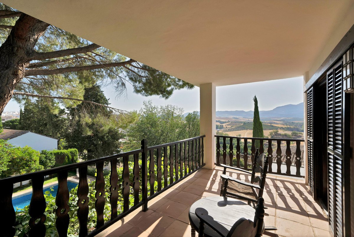 Balcony with wooden railing overlooking a pool and scenic mountains