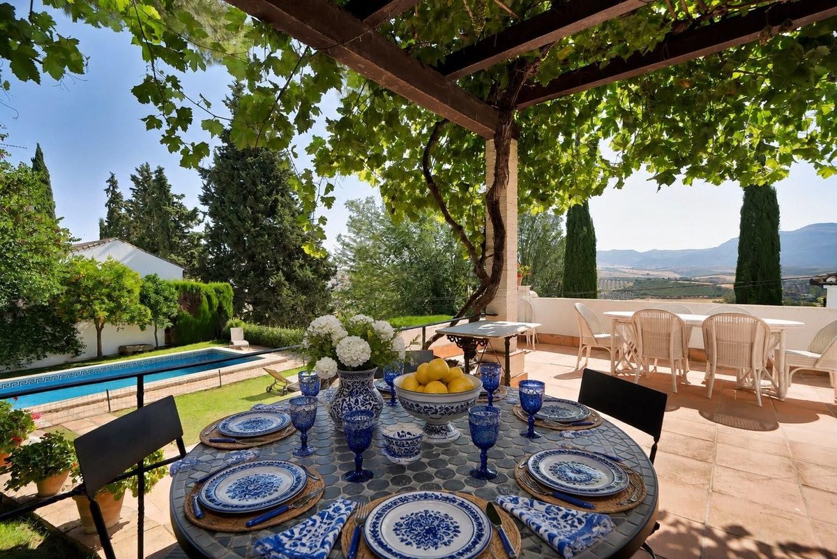 Outdoor dining area with blue and white tableware, swimming pool, and scenic view