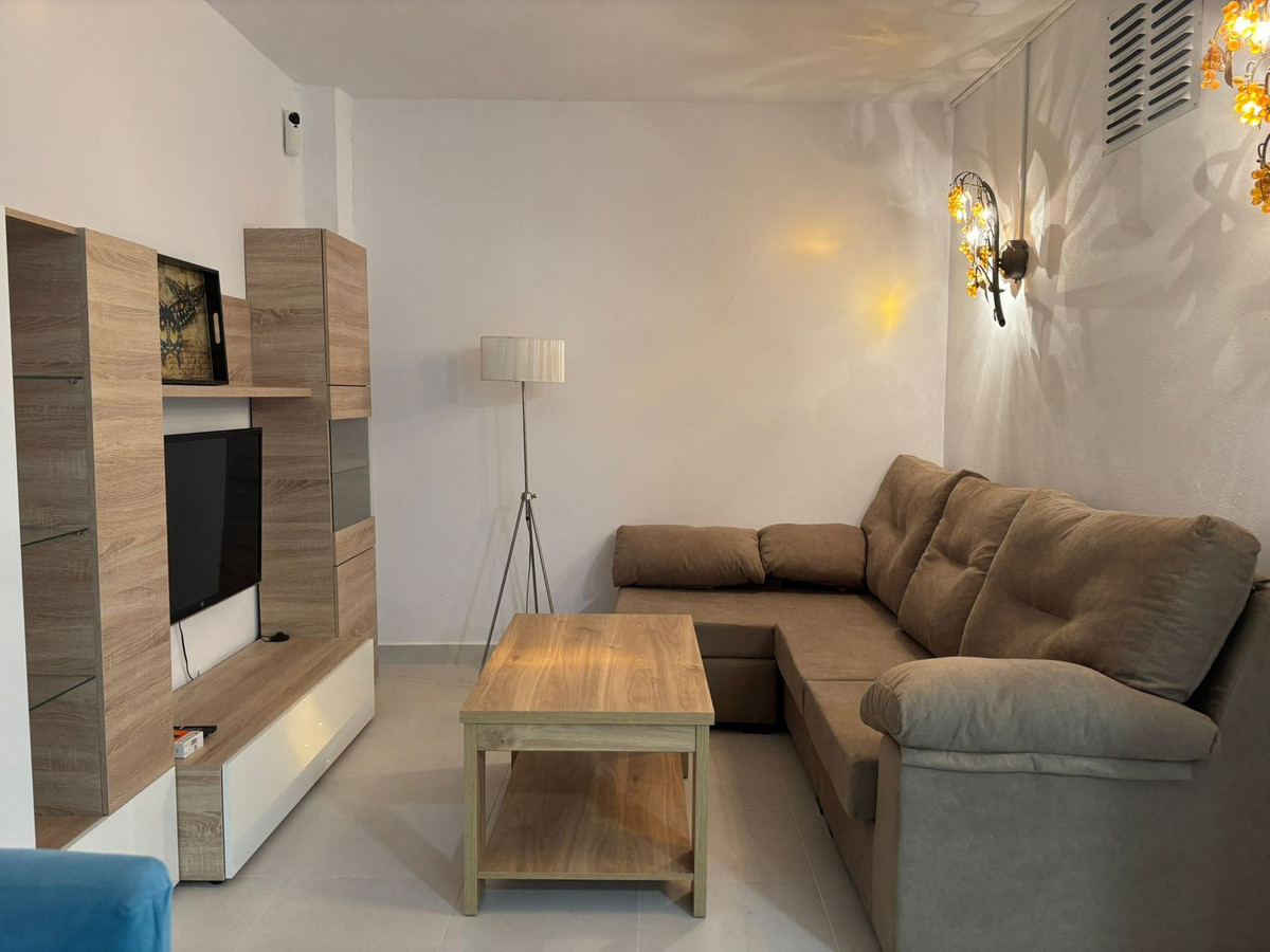 Gezellige woonkamer met houten meubels en comfortabele bank.