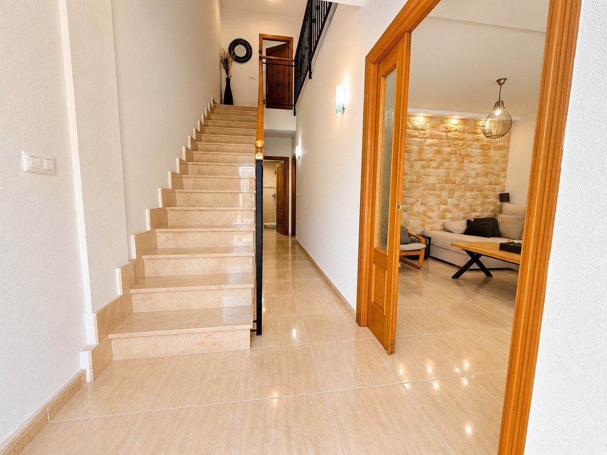 Modern hallway with marble stairs leading to living room with stone accent wall