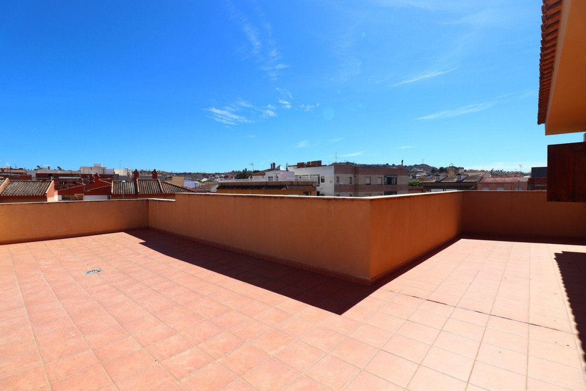 Spacious tiled terrace with terracotta walls, offering a panoramic city view under a clear blue sky.