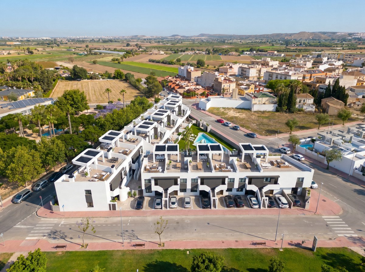 Modern apartment complex with rooftop terraces, swimming pools, and surrounding green spaces, offering distant views.