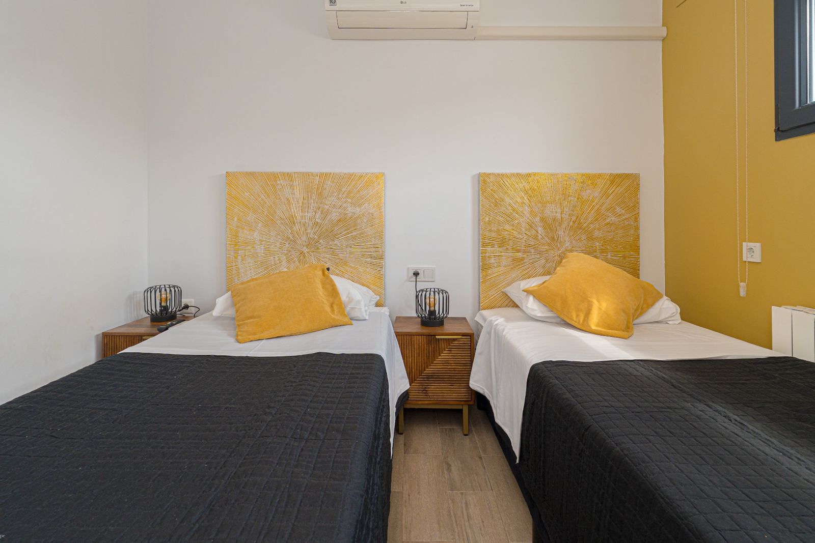 Tweepersoonskamer met gele accentmuur en bedden