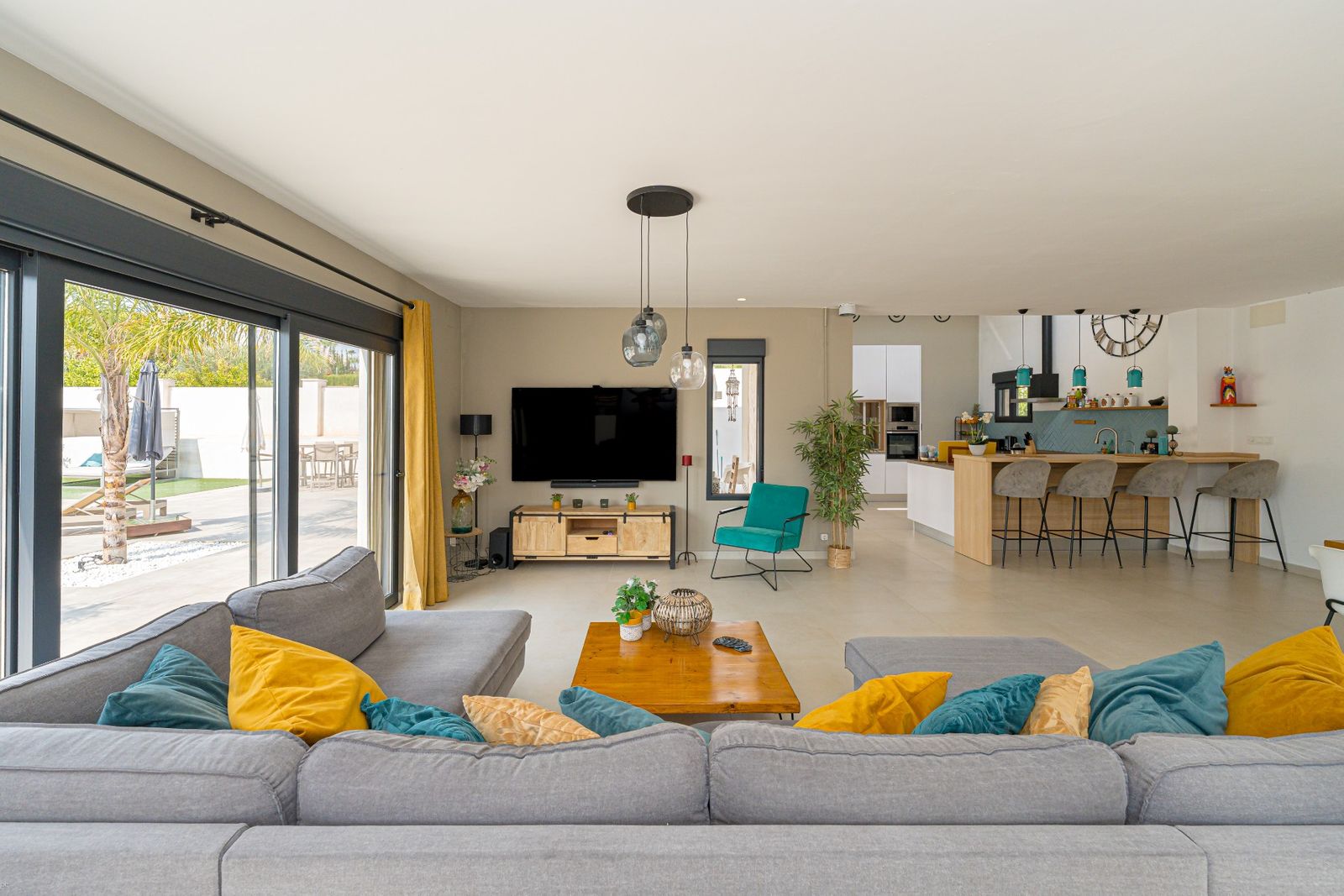 Moderne open woonkamer met keuken en toegang tot de tuin.