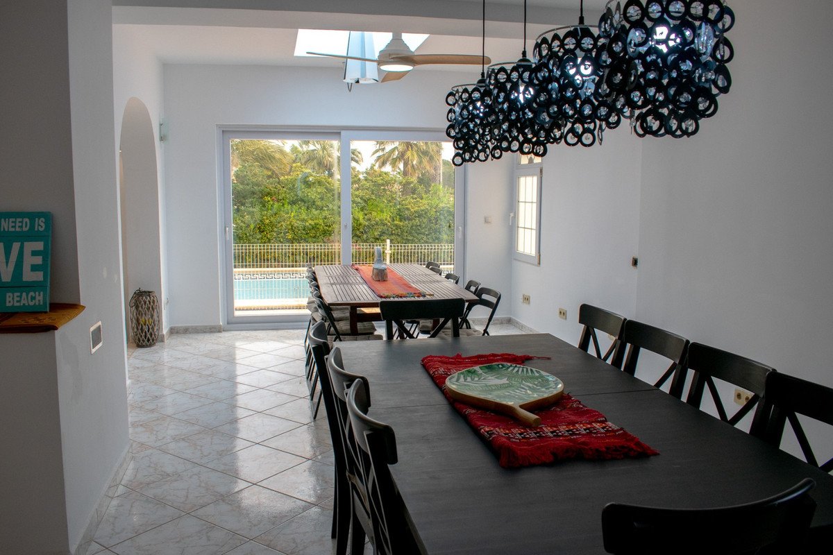 Dining room with pool view, black chandelier, and outdoor sliding doors
