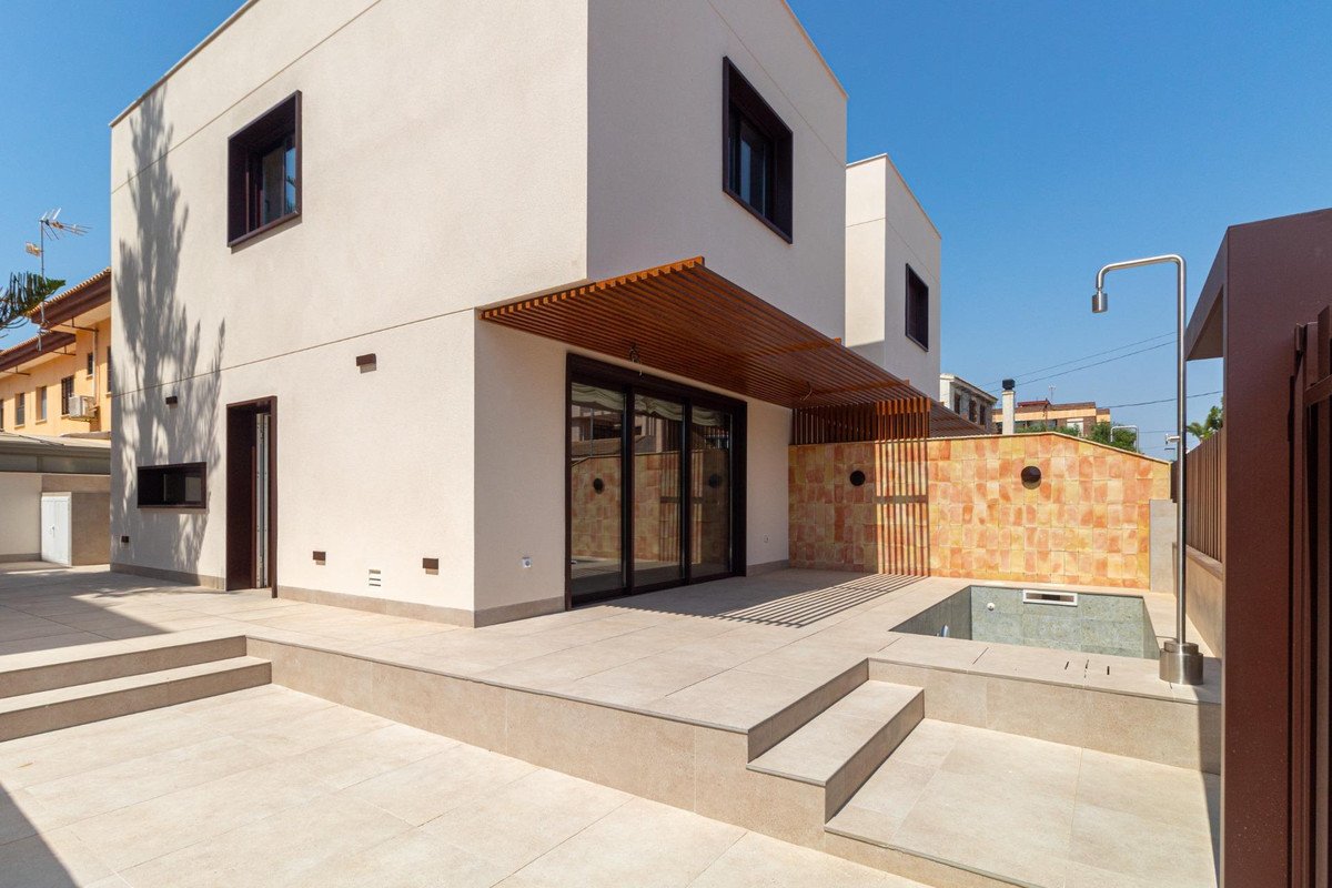 Modern house exterior with patio, small pool, and outdoor shower on a sunny day.