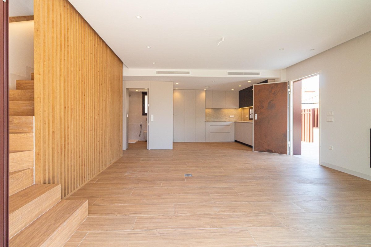 Spacious modern living area with a contemporary kitchen, wooden stairs, and access to an outdoor area.