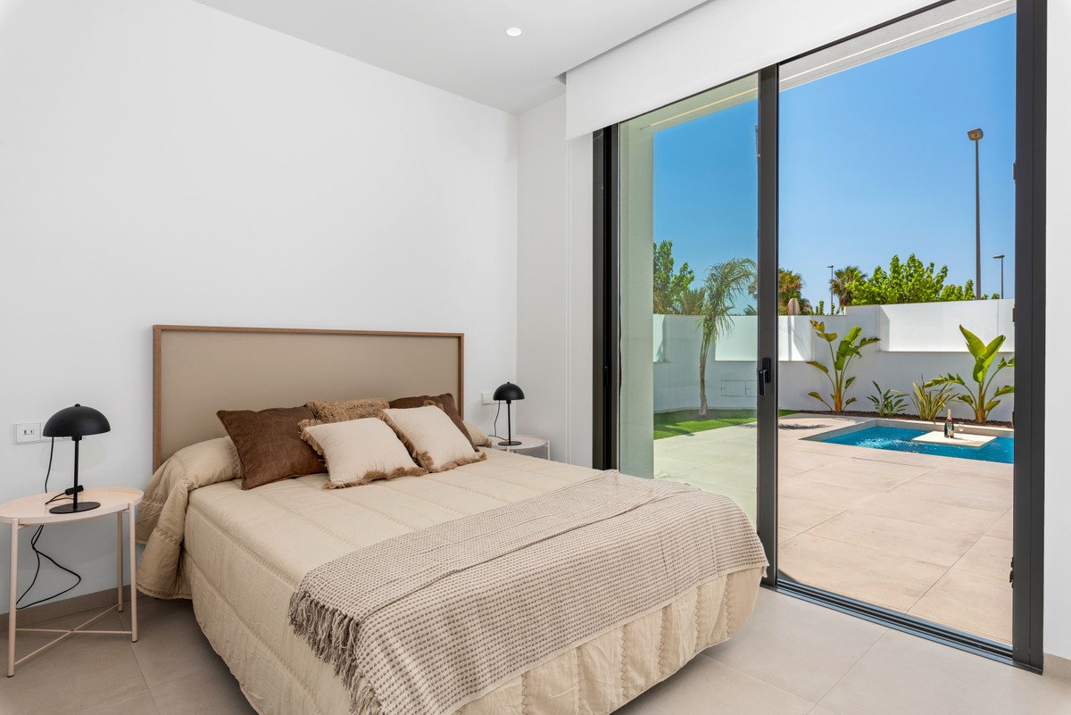Bedroom with a large bed and sliding glass doors opening to a private pool and garden area.
