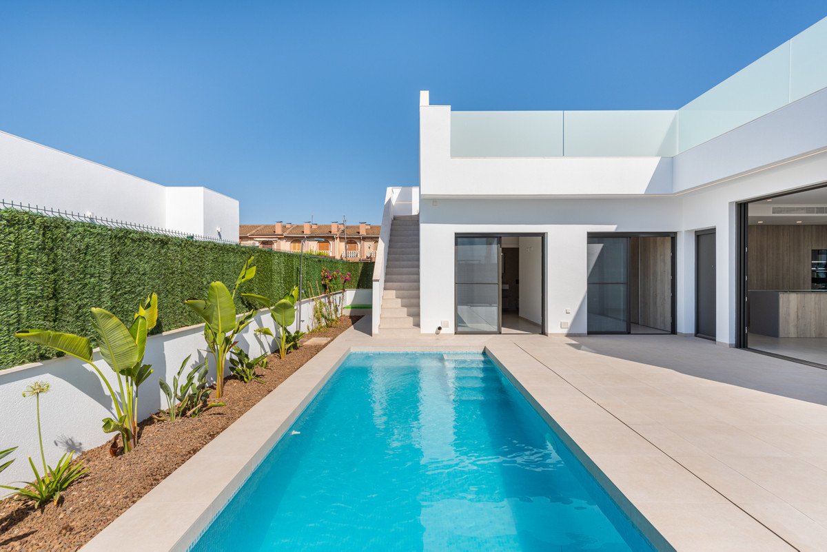 Modern home with a private swimming pool and patio, featuring large glass doors and lush greenery.