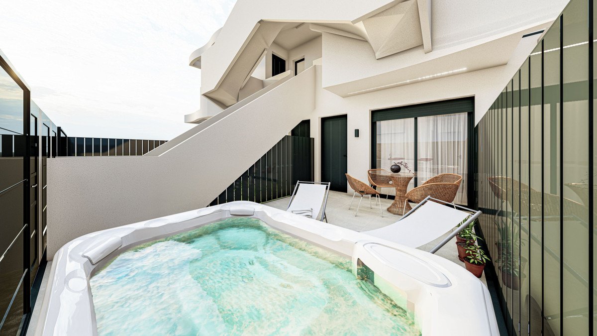 Outdoor terrace with a bubbling jacuzzi, lounge chairs, table, chairs, and modern architecture.