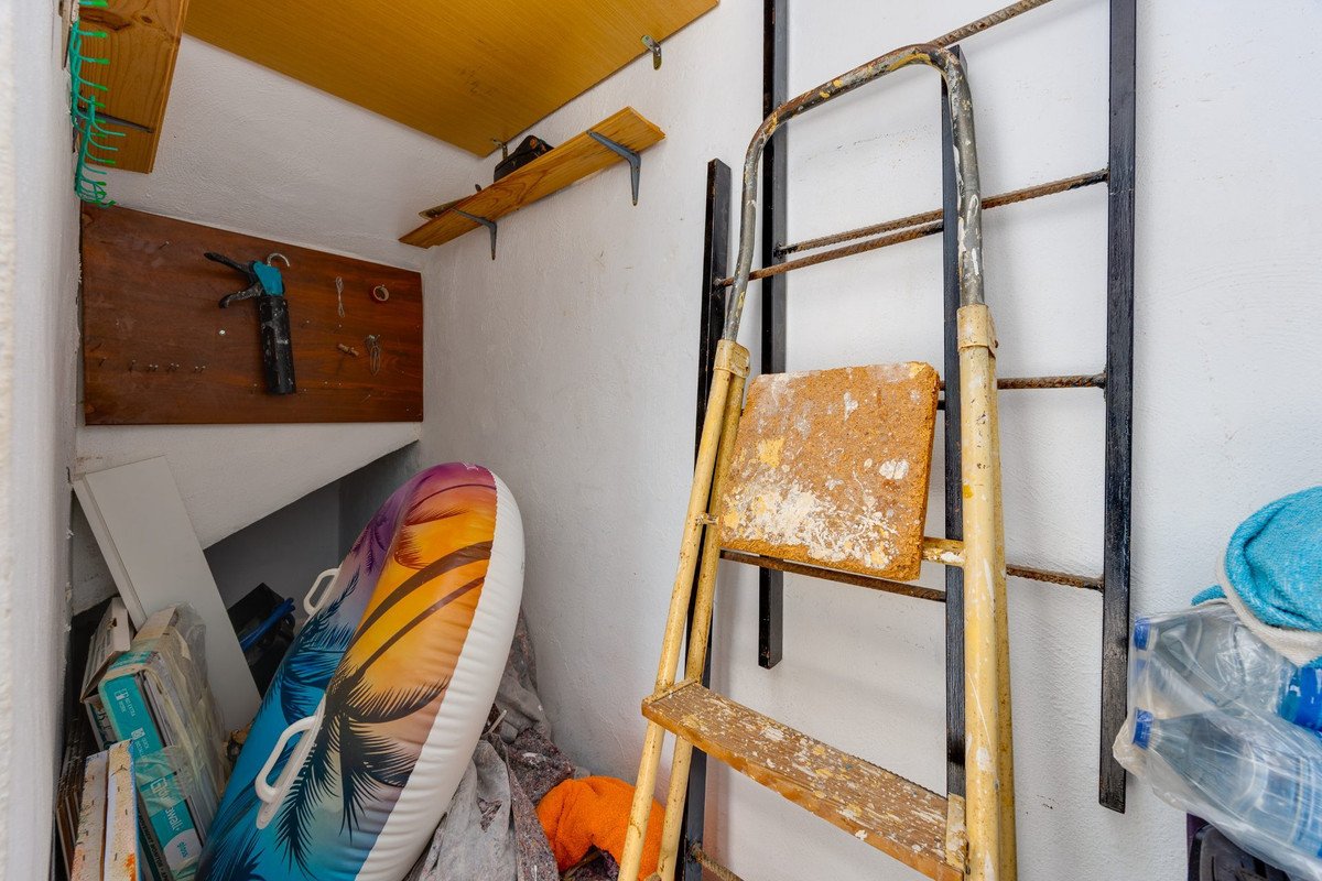 Storage area with a ladder, inflatable pool float, and various items on shelves.