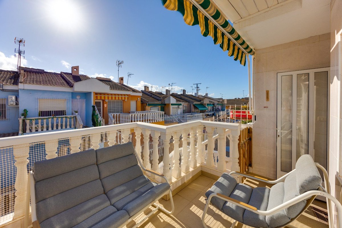 Terrace with outdoor seating and view of colorful houses under a sunny blue sky.