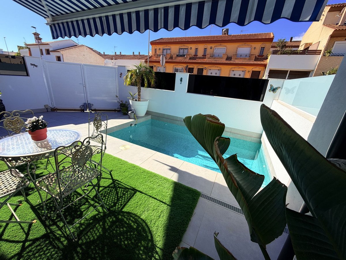 A small private pool with outdoor seating area and a table on a sunny day.